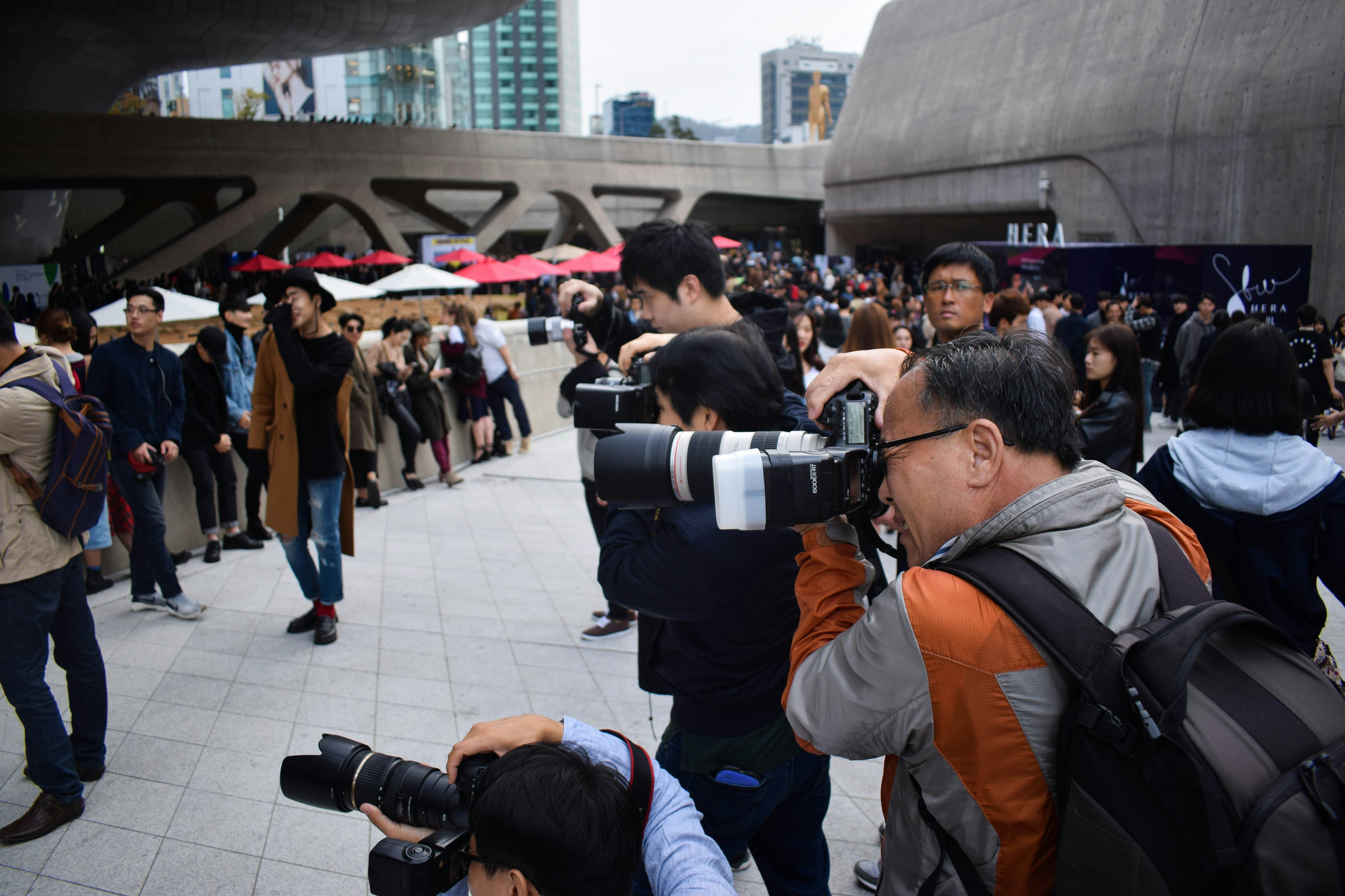 group of photographers holding DSLR cameras in event during daytime